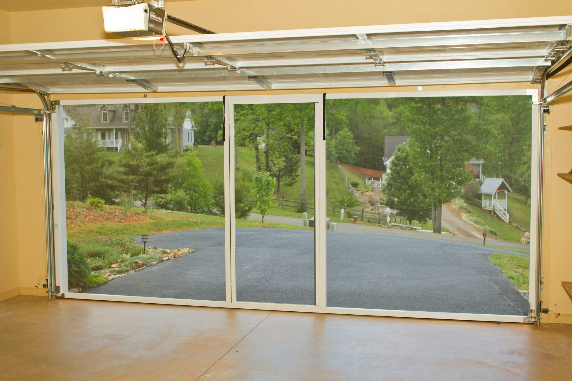 Retractable garage door screen panels with scenic yard view